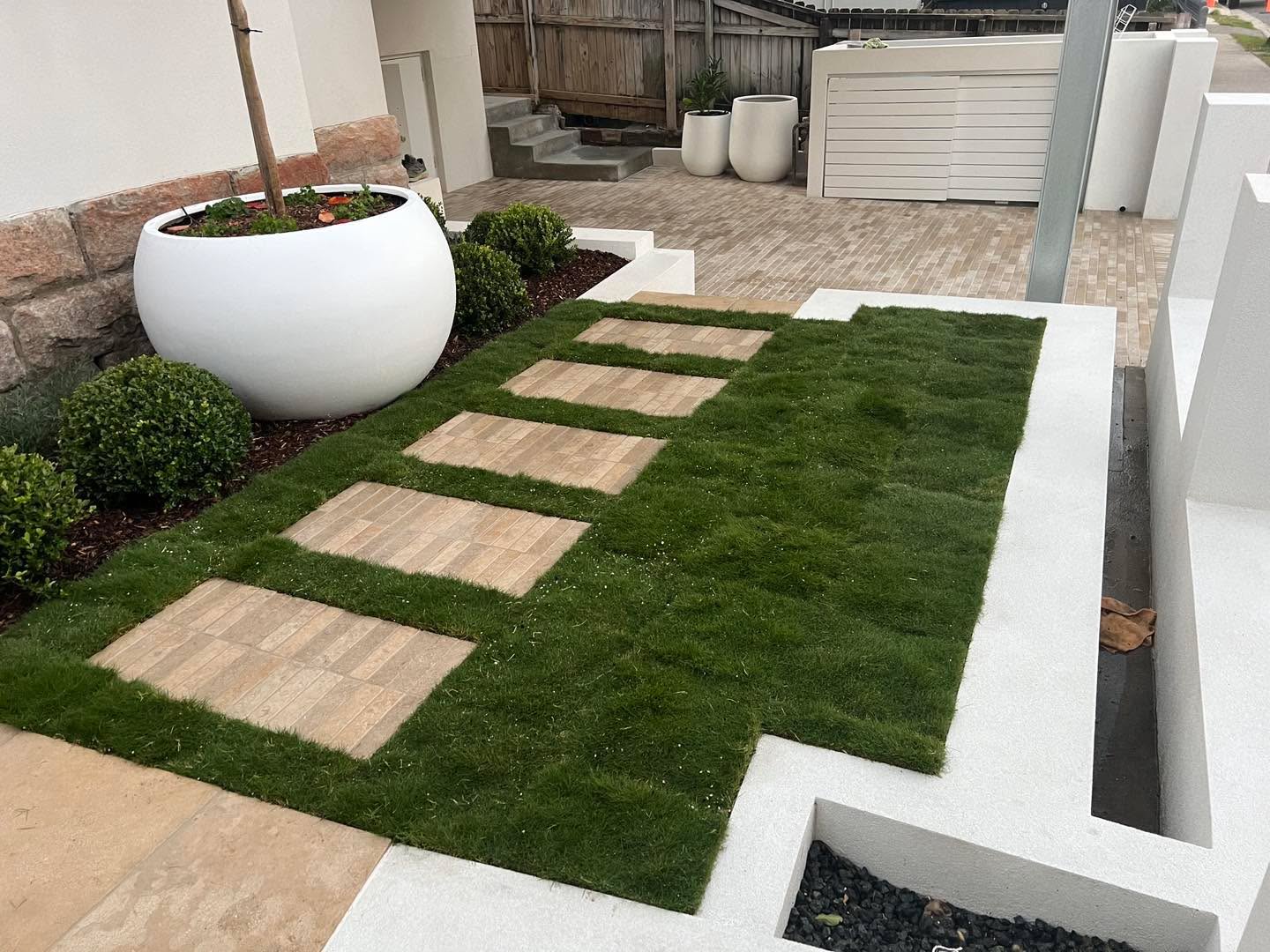 Pristine artificial turf lawn edged with charcoal pavers in a modern courtyard